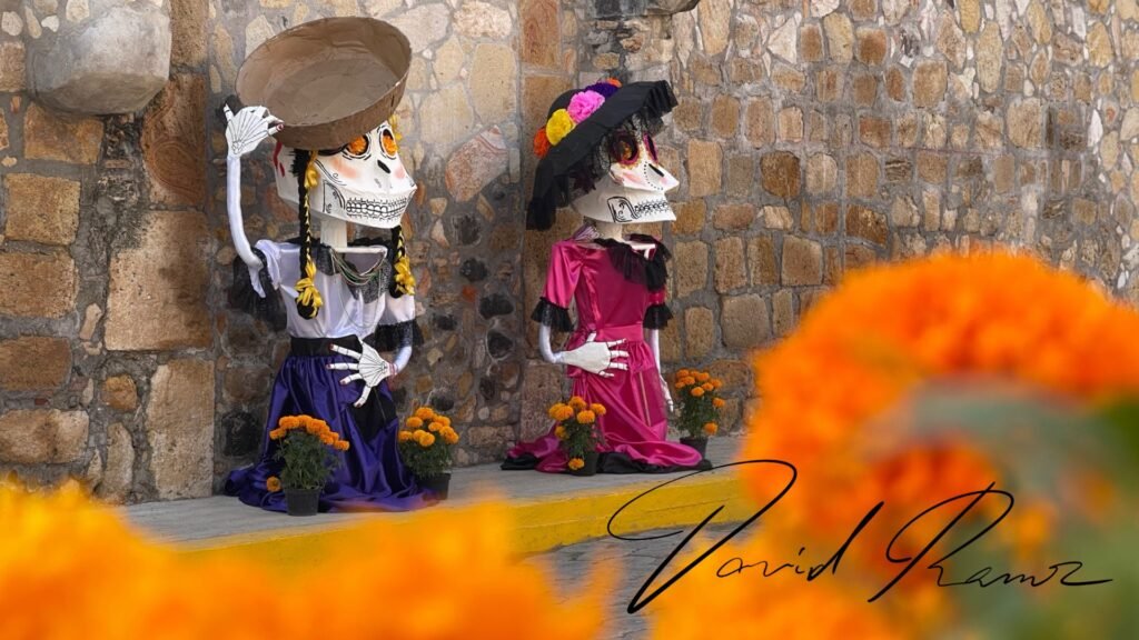 Catrinas de papel maché con cempasúchil frente a un muro de piedra en Huaquechula, Puebla