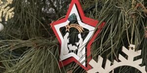 Adorno en forma de estrella con escena de la Natividad colgado en un árbol de Navidad natural.